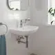 Wandmontiertes Waschbecken mit verchromtem Wasserhahn von Grohe, Handtuchhalter und Pflanze im Hintergrund, helle Fliesen an der Wand.