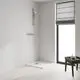 Duschbereich mit verchromter Grohe-Brausegarnitur, inklusive Handbrause und Schlauch. Neben dem Duschbereich befindet sich ein Tisch mit Hygieneprodukten.