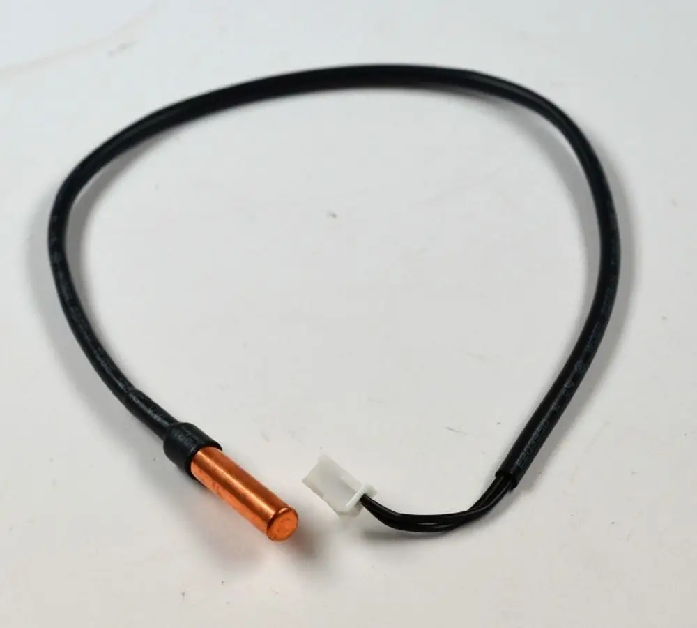 Sensor mit einem kupfernen Gehäuse und schwarzen Kabeln, der zu einem Remko-Gerät gehört. Stecker im Bild sichtbar.