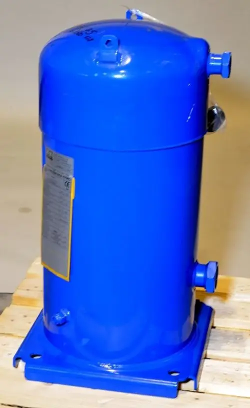 Blauer Kompressor von Remko auf Holzpalette, mit mehreren Anschlüssen an der Ober- und Unterseite. Eine technische Beschreibung ist an der Seite angebracht.