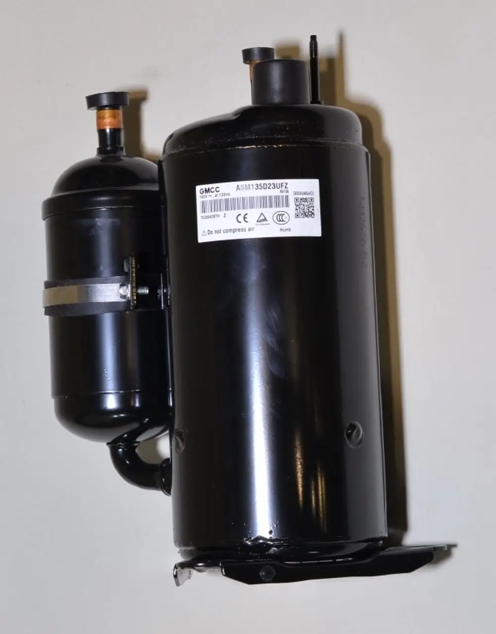 Schwarzer Kompressor von Remko mit einer zylindrischen Form und zwei Anschlüssen. Auf der Oberfläche befindet sich ein Typenschild mit technischen Angaben.