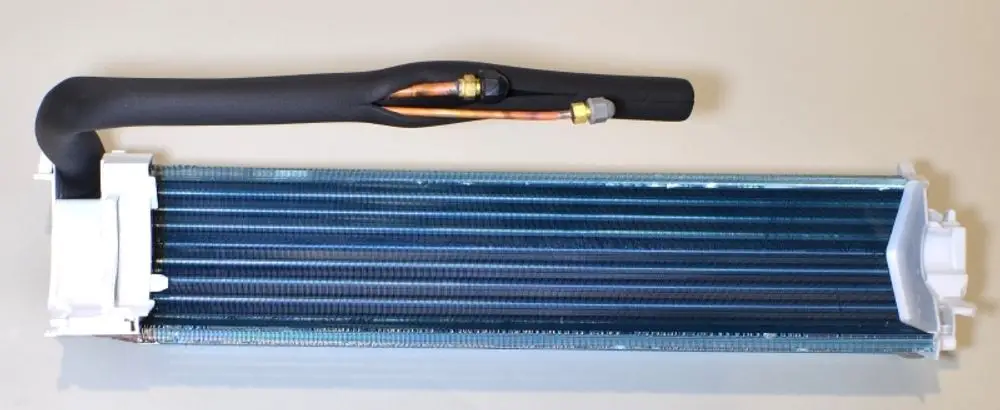 Verdampfer von Remko mit einem langen, lamellenförmigen Wärmetauscher und zwei angeschlossenen Kupferleitungen. Transparentes Gehäuse an beiden Enden sichtbar.