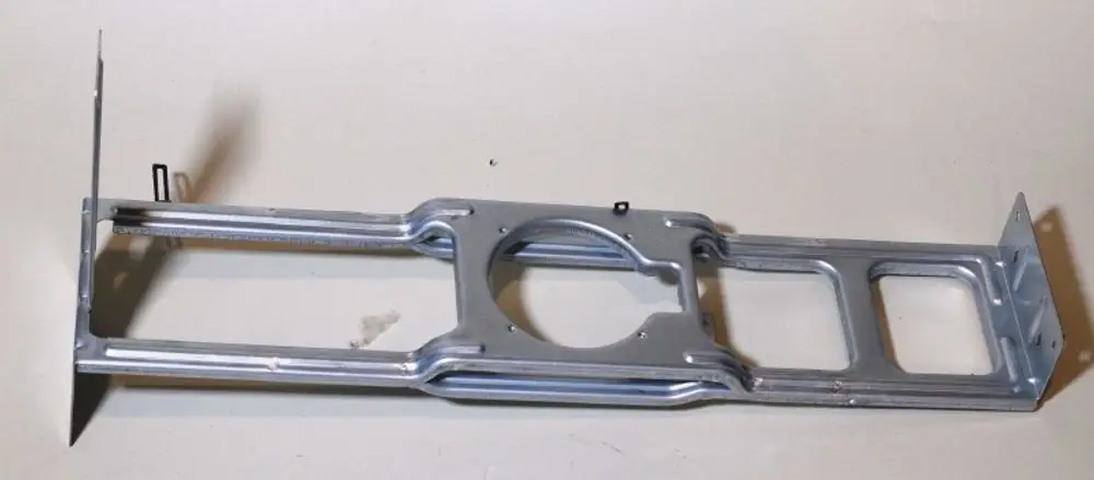 Halterung aus Metall für einen Ventilatormotor, gefertigt von Remko. Die Struktur ist länglich und weist Aussparungen zur Befestigung auf.