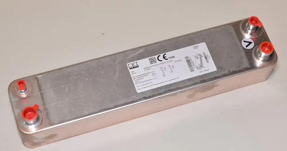 Remko Wärmetauscher in länglicher Form mit zwei Anschlüssen an den Enden. Die Oberseite ist metallisch und eine Produktinformation ist auf der Seite angebracht.