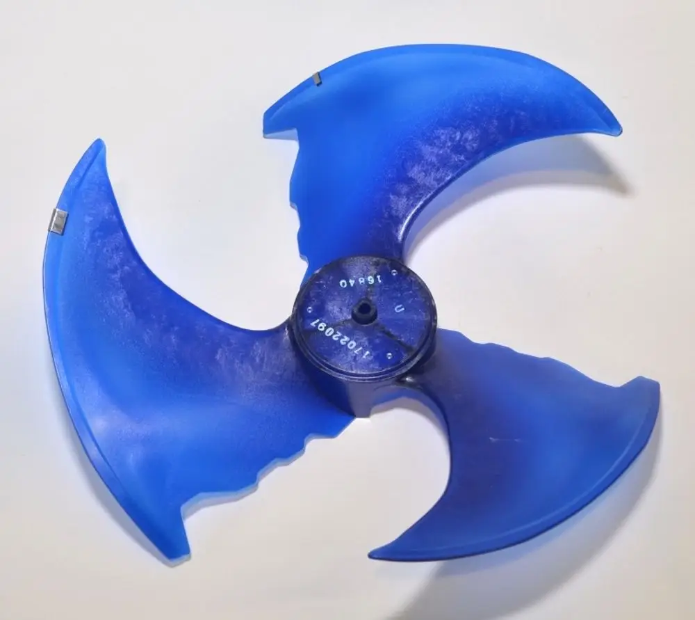 Blauer Ventilatorflügel mit drei Flügeln, montiert auf einer zentralen Halterung. Teil eines Heiz- oder Klimageräts von Remko.