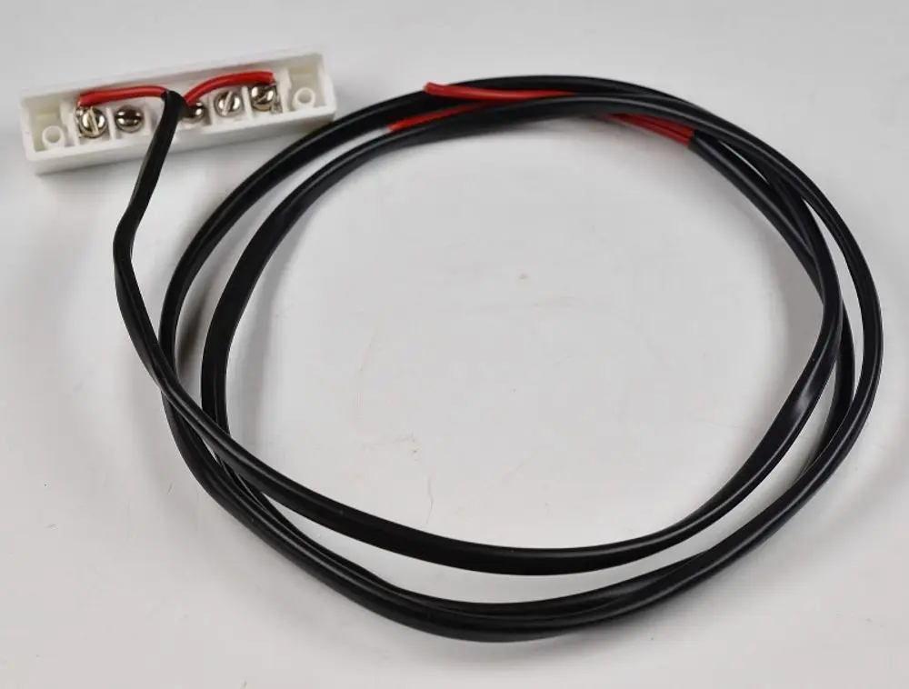 Schwarz-rotes Kabel mit Anschlussklemmen auf einer weißen Platine. Teil eines elektrischen Schaltkreises von Remko, möglicherweise für einen Magnetschalter.