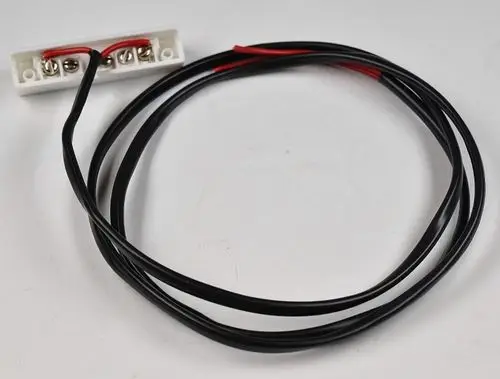 Schwarz-rotes Kabel mit Anschlussklemmen auf einer weißen Platine. Teil eines elektrischen Schaltkreises von Remko, möglicherweise für einen Magnetschalter.
