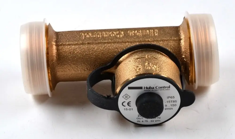 Durchflusssensor mit Metallgehäuse und zwei transparenten Anschlüssen. Hersteller: Remko. Montiert ist eine schwarze Verstellhilfe an der Seite.