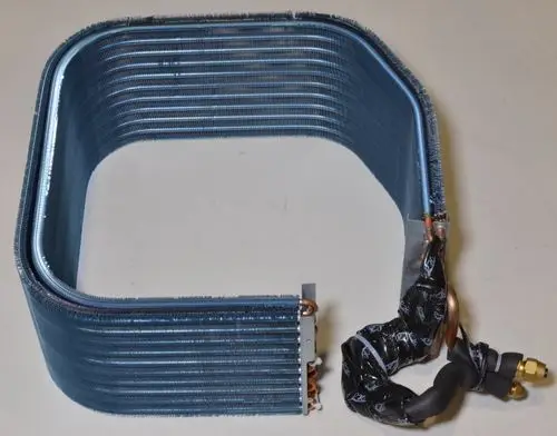 Verdampfer von Remko mit gebogenem Rohrdesign, mehreren Lamellen zur Kontaktfläche und einer Anschlussseite für die Verbindung mit Kühlmitteln.