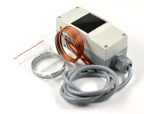 Frostschutzthermostat von Remko mit einem Gehäuse, einem senkrechten Kupferrohr, einem grauen Kabel und Zubehörteilen in einer transparenten Verpackung.