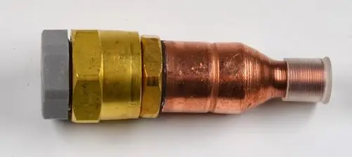 Schnellkupplung aus Kupfer und Messing, hergestellt von Remko, zur Verbindung von Einspritzleitungen in technischen Anwendungen.