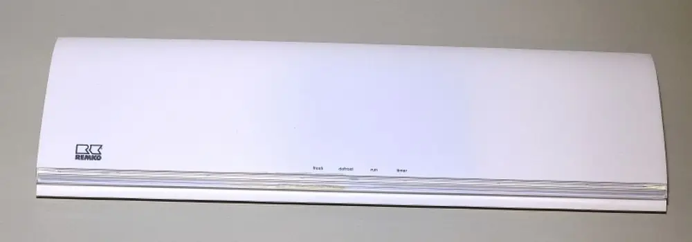Weiße Geräteblende von Remko mit glatter Oberfläche und vier Tasten für Funktionen, abgebildet vor einer grauen Wand.