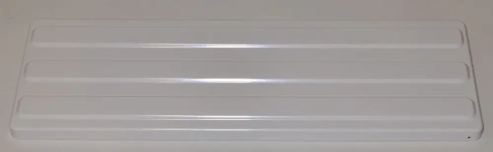Weißes, flaches Blech mit mehreren Rillen, möglicherweise zur Abdeckung oder Befestigung, von der Marke Remko. Bodennaht lässt eine Montage an einer Wand vermuten.