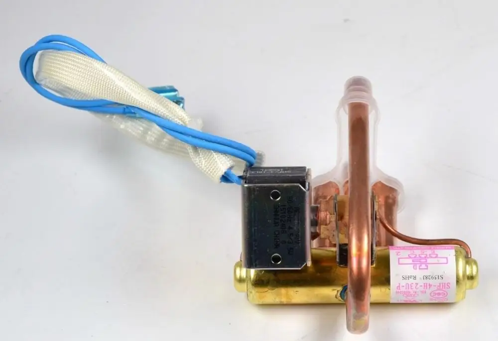 Umkehrventil von Remko mit einer Kupferleitung und einem Elektromagneten. Das Produkt ist mit Kabeln ausgestattet und zeigt eine robuste Bauweise.