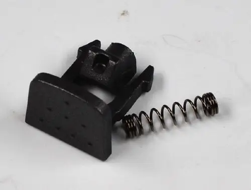Schwarzer Druckknopf mit einer flachen Basis und einer Feder, geeignet für die Montage in Geräte von Remko, einschließlich einem Aufnahmepunkt für die Befestigung.
