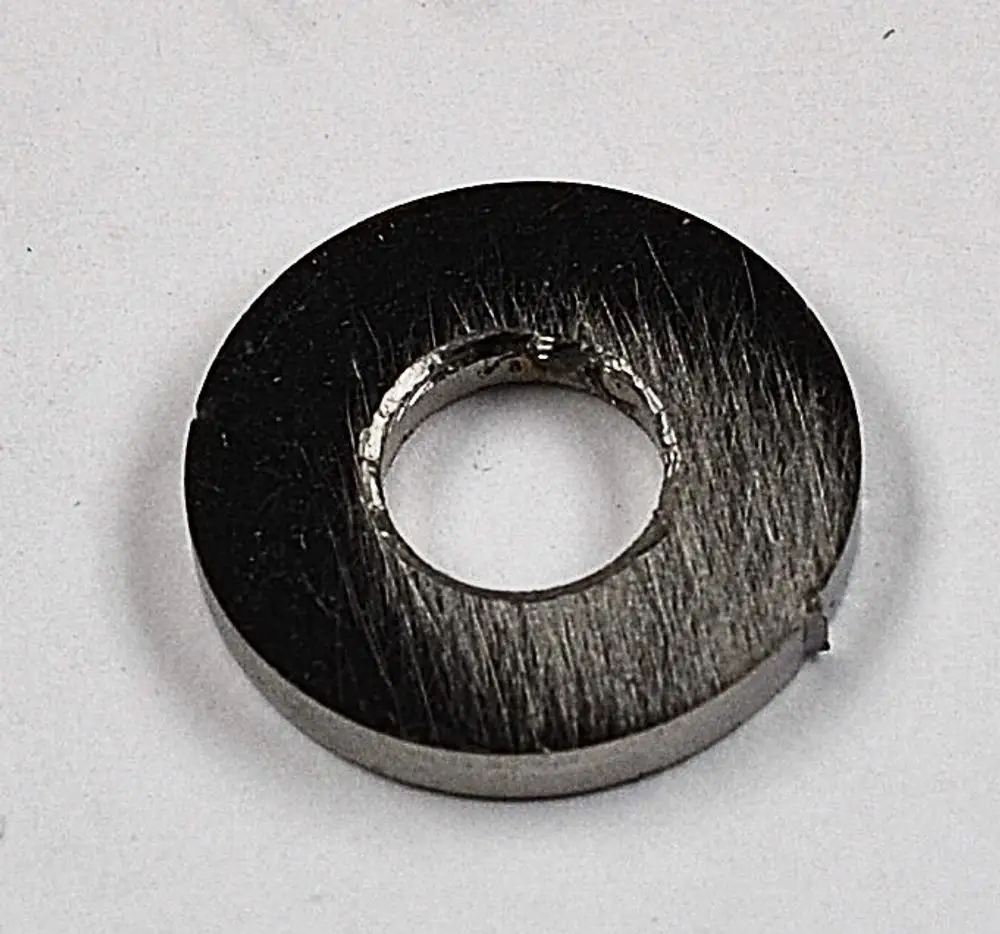 Metallische Scheibe mit zentralem Loch und gebürsteter Oberfläche, möglicherweise Teil eines technischen Produkts der Marke Remko.