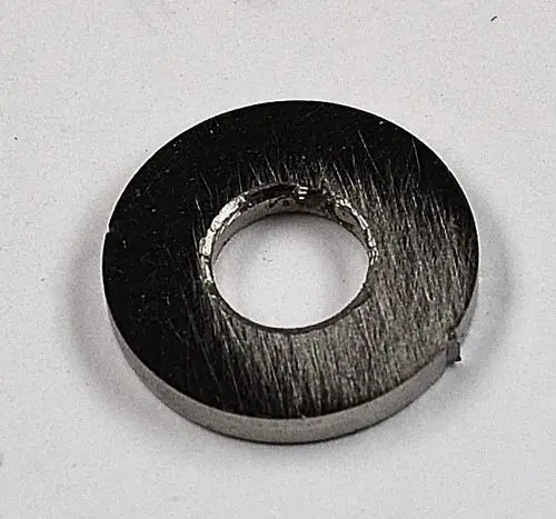 Metallische Scheibe mit zentralem Loch und gebürsteter Oberfläche, möglicherweise Teil eines technischen Produkts der Marke Remko.