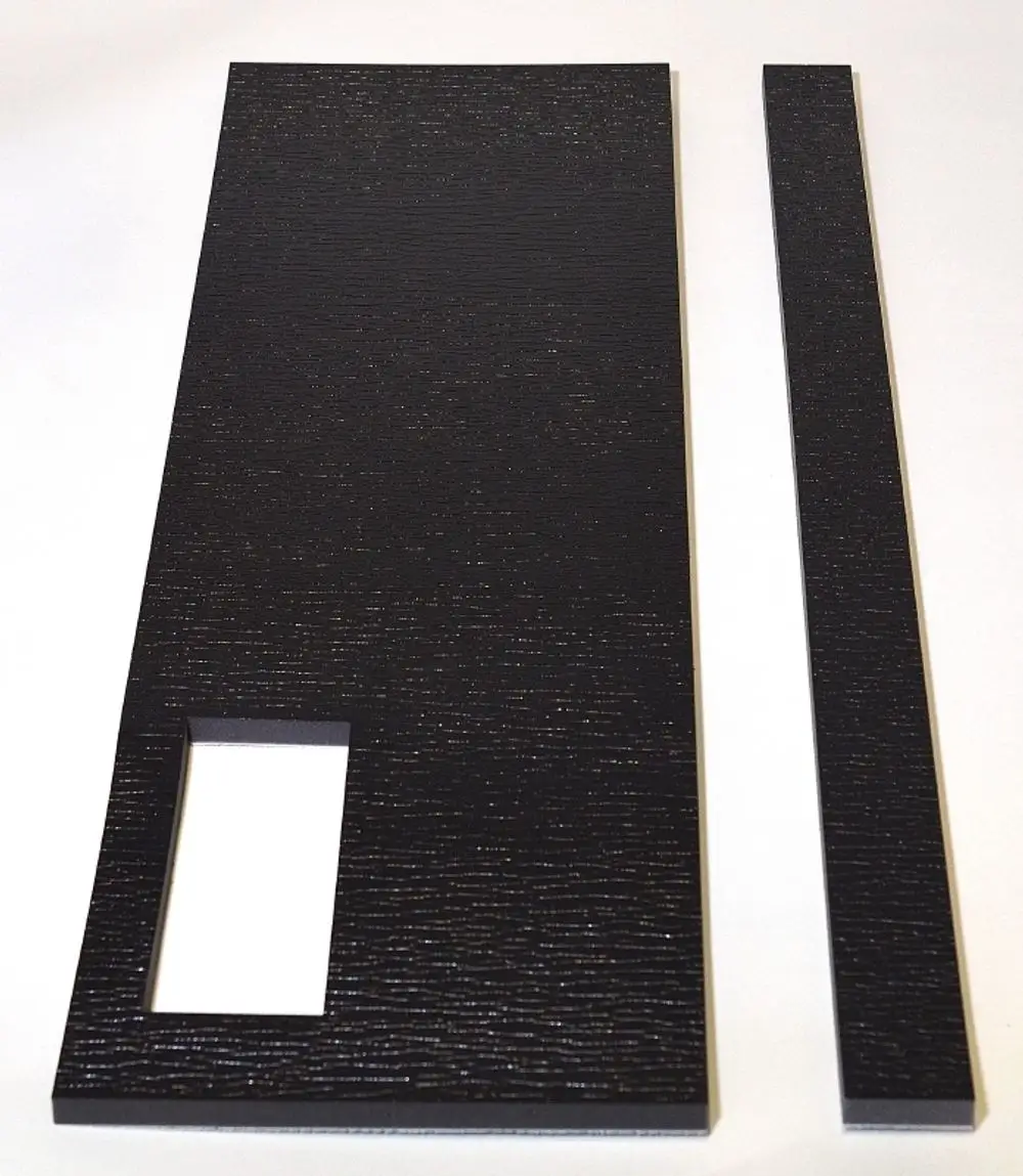 Schwarze Dämmplatten von Remko, eine große Platte mit rechteckigem Ausschnitt und eine schmale lange Platte. Strukturierte Oberfläche, auf hellem Hintergrund.