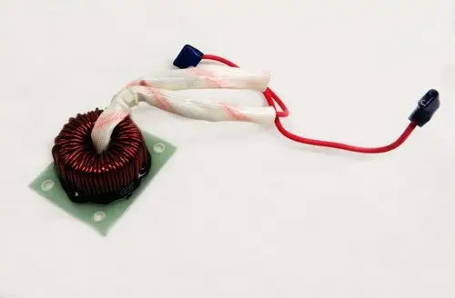 Drosselspule mit kupferner Wicklung, befestigt auf einer grünen Platte, mit zwei elektrischen Anschlüssen. Produkt von Remko.