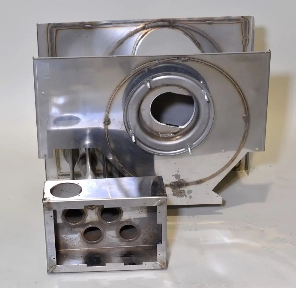 Metallisches Bauteil, hergestellt von Remko, bestehend aus mehreren Teilen mit Öffnungen und Schweißnähten, vermutlich Teil eines Brennsystems.