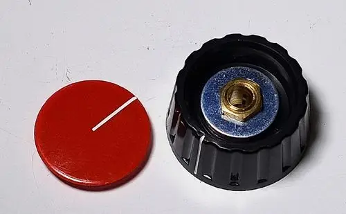 Schwarzer Stellknopf mit goldfarbener Gewindemutter in der Mitte und rotem Deckel daneben. Das Produkt stammt von der Marke Remko.