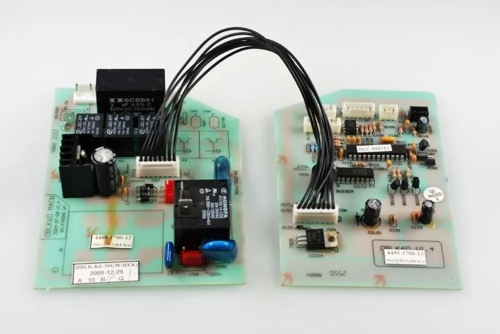Zwei Steuerplatinen von Remko, verbunden durch Kabel, mit verschiedenen elektronischen Bauteilen wie Relais, Widerständen und Kondensatoren.