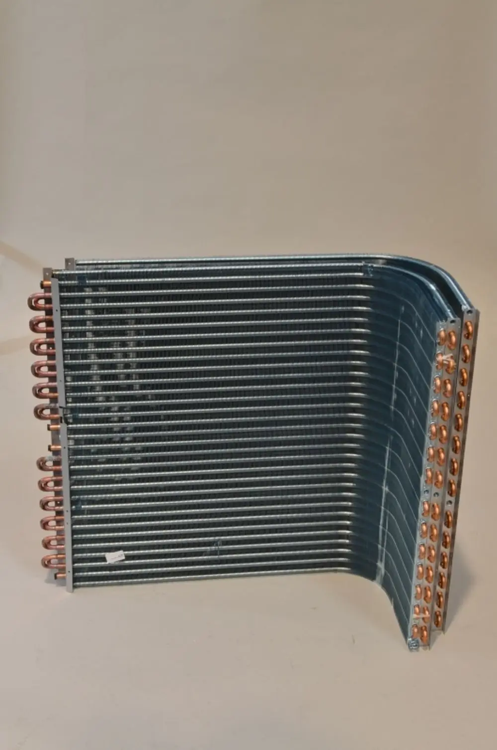 Lamellenverflüssiger von Remko mit mehreren Kühlschlangen und Kupferanschlüssen, in gebogener Form, auf hellem Hintergrund abgebildet.