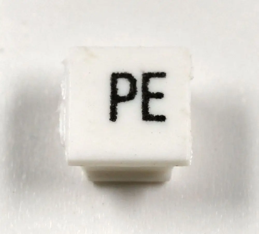Weiße Klemmenmarkierung mit schwarzen Buchstaben "PE", hergestellt von Remko, auf einer glatten, hellen Oberfläche.
