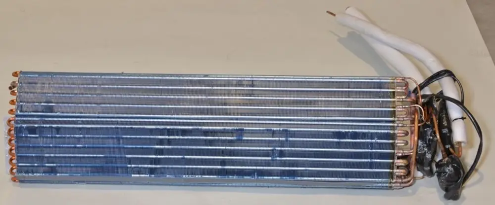Wärmetauscher von Remko, gefertigt aus Kupferrohren und Aluminiumlamellen, mit zwei Anschlussleitungen, senkrecht angeordnet.