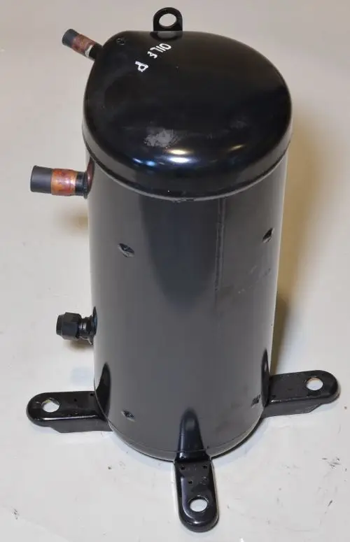 Schwarzer Kompressor von Remko mit zwei Anschlüssen und Befestigungslöchern an der Basis, auf einem neutralen Hintergrund.