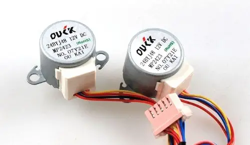 Zwei kleine Gleichstrommotoren mit farbigen Drähten und einer weißen Anschlussbuchse, Marke Remko, für verschiedene Anwendungen in der Elektrotechnik.