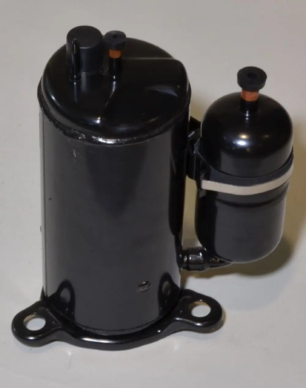 Schwarzer Kompressor mit zwei angeschlossenen Ventilen, hergestellt von Remko. Das Design zeigt eine zylindrische Form und eine Montagebasis mit Löchern.