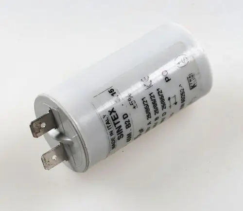 Weißer Kondensator mit Metall-Anschlüssen, beschriftet mit "Remko" und technischen Daten. Gerät zur Energiespeicherung in elektrischen Anwendungen.