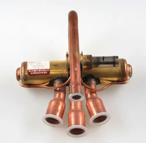 Umkehrventil der Marke Remko mit mehreren Kupferrohren und einem transparenten Bereich, montiert auf einer Metallbasis.