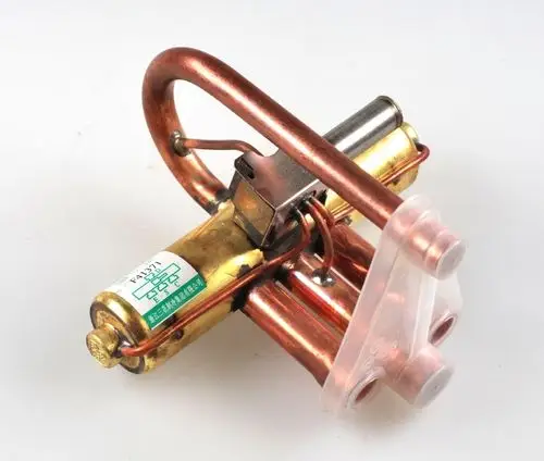 Umkehrventil von Remko mit zwei Kupferrohren und einer Anschlussplatte. Das Produkt weist eine kompakte Bauweise auf und wird typischerweise in Kühlsystemen eingesetzt.