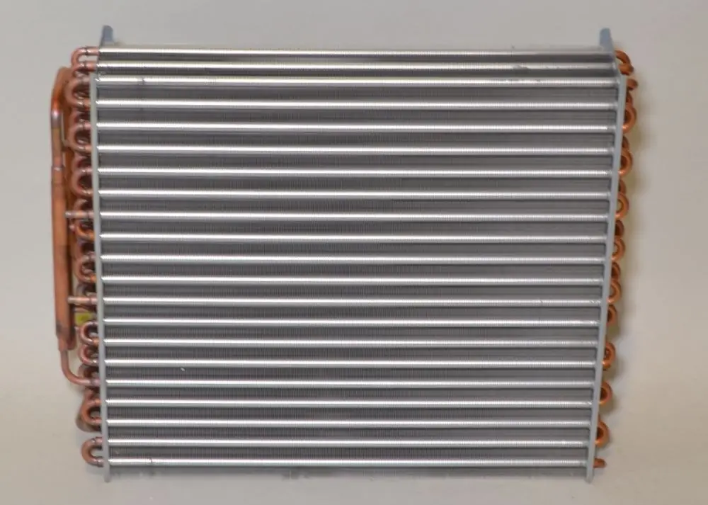 Verflüssiger von Remko mit horizontalen Metallrippen und Kupferrohren, montiert auf einer hellen Oberfläche.