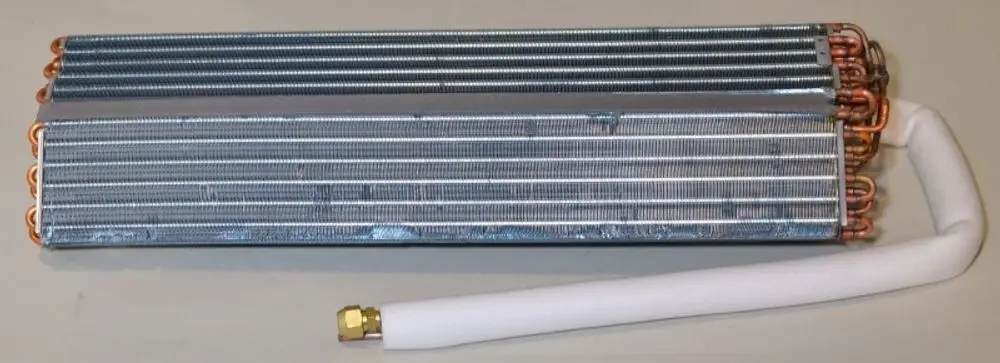 Verdampfer von Remko mit mehreren Kupferrohren und Aluminiumlamellen, auf einer hellen Oberfläche liegend. Ein Anschlussrohr ist isoliert.