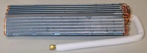 Verdampfer von Remko mit mehreren Kupferrohren und Aluminiumlamellen, auf einer hellen Oberfläche liegend. Ein Anschlussrohr ist isoliert.