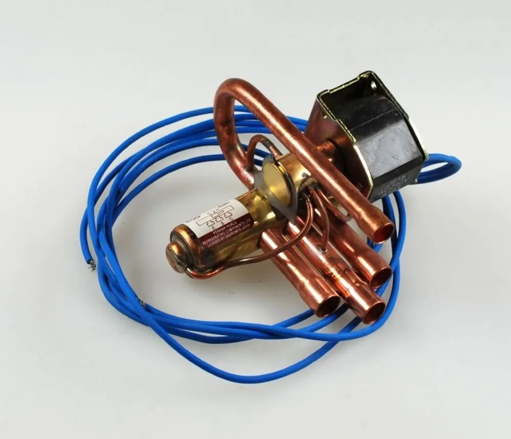 Umkehrventil von Remko mit Kupferrohren und elektrischen Kabeln, auf hellem Hintergrund. Das Produkt zeigt eine kompakte Bauweise zur Regelung von Kältemitteln.