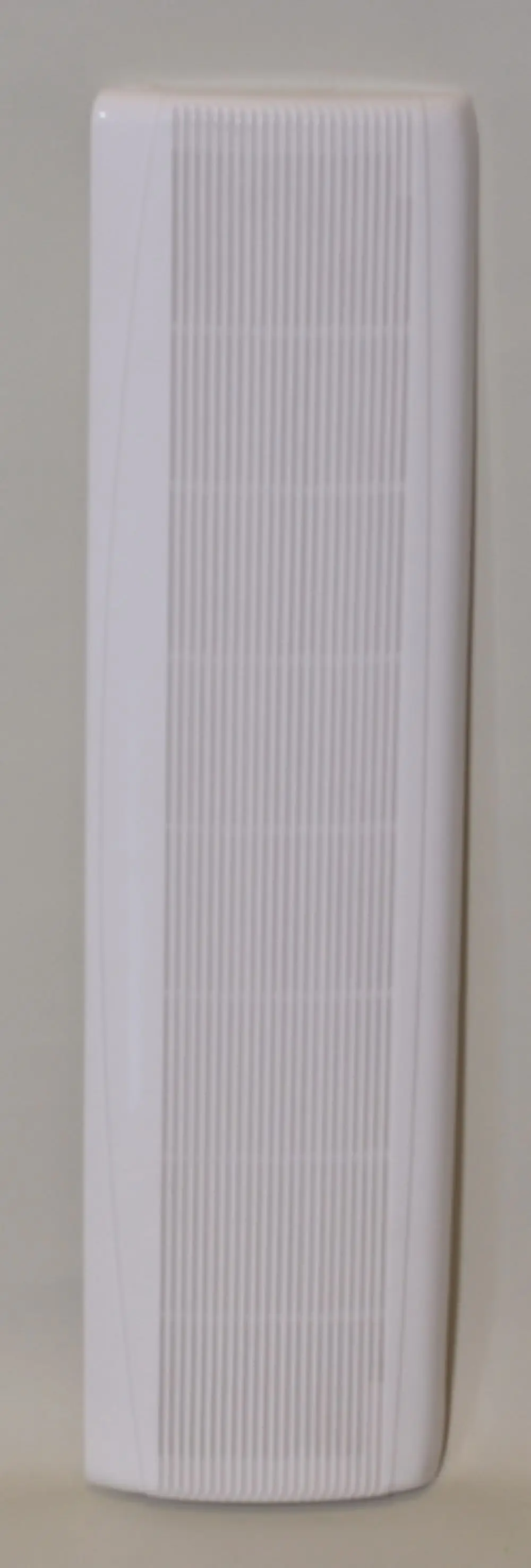 Weißes Ansauggitter von Remko mit vertikalen Rillen, montiert an einer hellen Wand. Das Gitter hat eine schlanke, rechteckige Form.