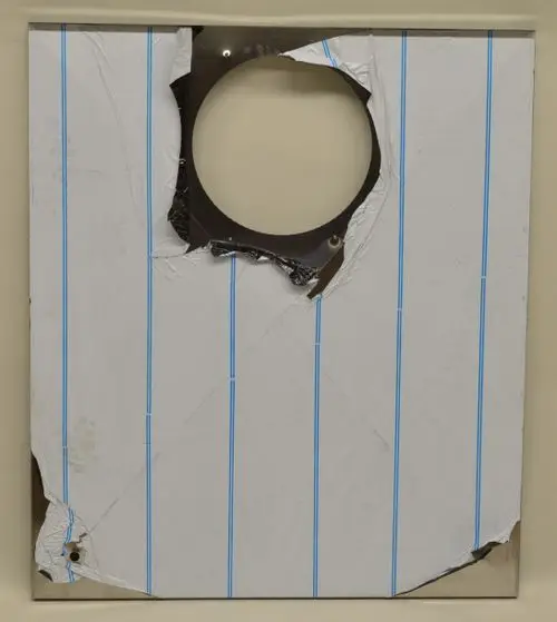 Deckblech von Remko, hintere Seite mit ausgerissener Stelle und Löchern, teilweise beschädigt, beschichtet mit weißem Papier und blauen Linien.