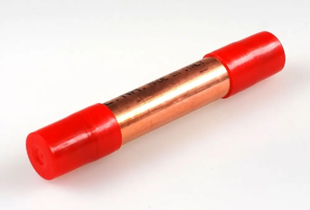 Kupferner Trockenfilter mit roten Kunststoffkappen. Der Filter stammt von der Marke Remko und wird in der Klimatechnik eingesetzt.