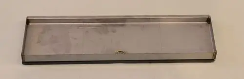 Kondensatfalle aus Metall mit flachem Design und einer zentralen Aussparung. Die Konstruktion ist stabil und eignet sich für den Einsatz in Verbindung mit Geräten von Remko.