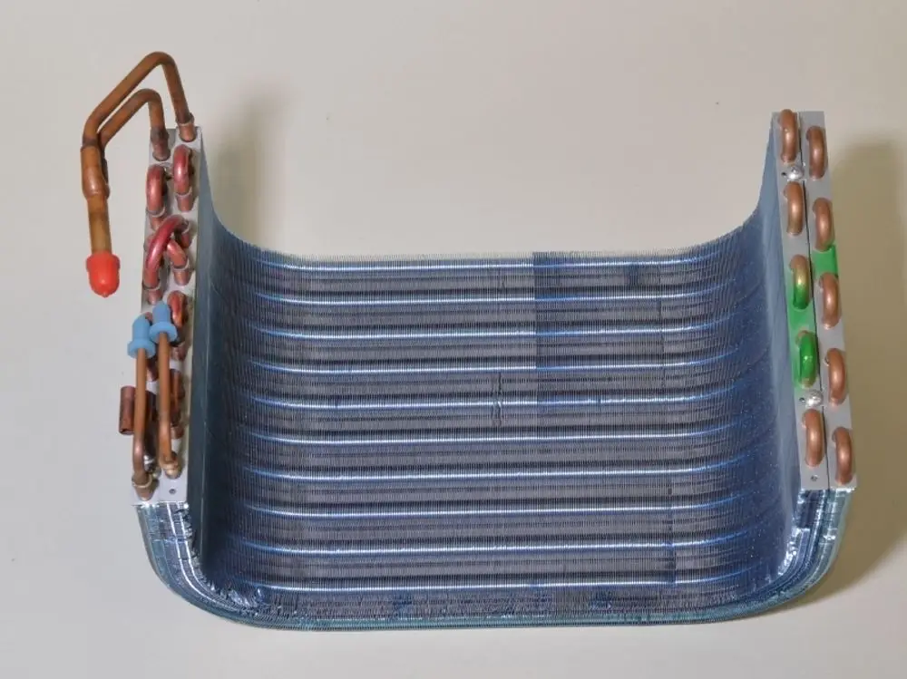 Verdampfer von Remko mit Kupferrohren und Aluminiumlamellen. Der Wärmetauscher hat eine gebogene Form und eine blaue Oberfläche.