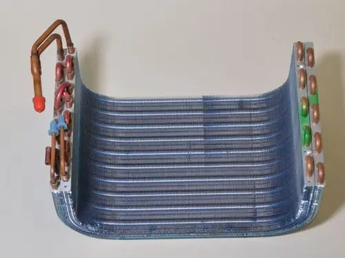 Verdampfer von Remko mit Kupferrohren und Aluminiumlamellen. Der Wärmetauscher hat eine gebogene Form und eine blaue Oberfläche.