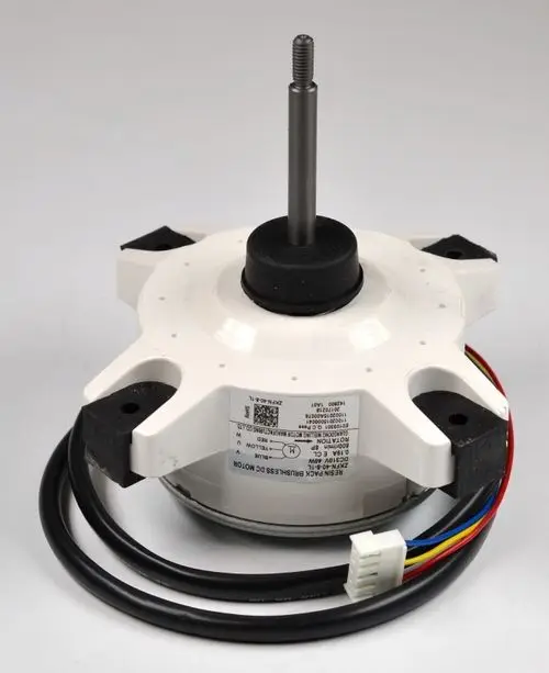 Remko Ventilatormotor mit schwarzem Gummi Fuß und Metallwelle, umgeben von Kabeln in verschiedenen Farben, auf hellem Hintergrund. Technische Informationen sind am Gehäuse angebracht.