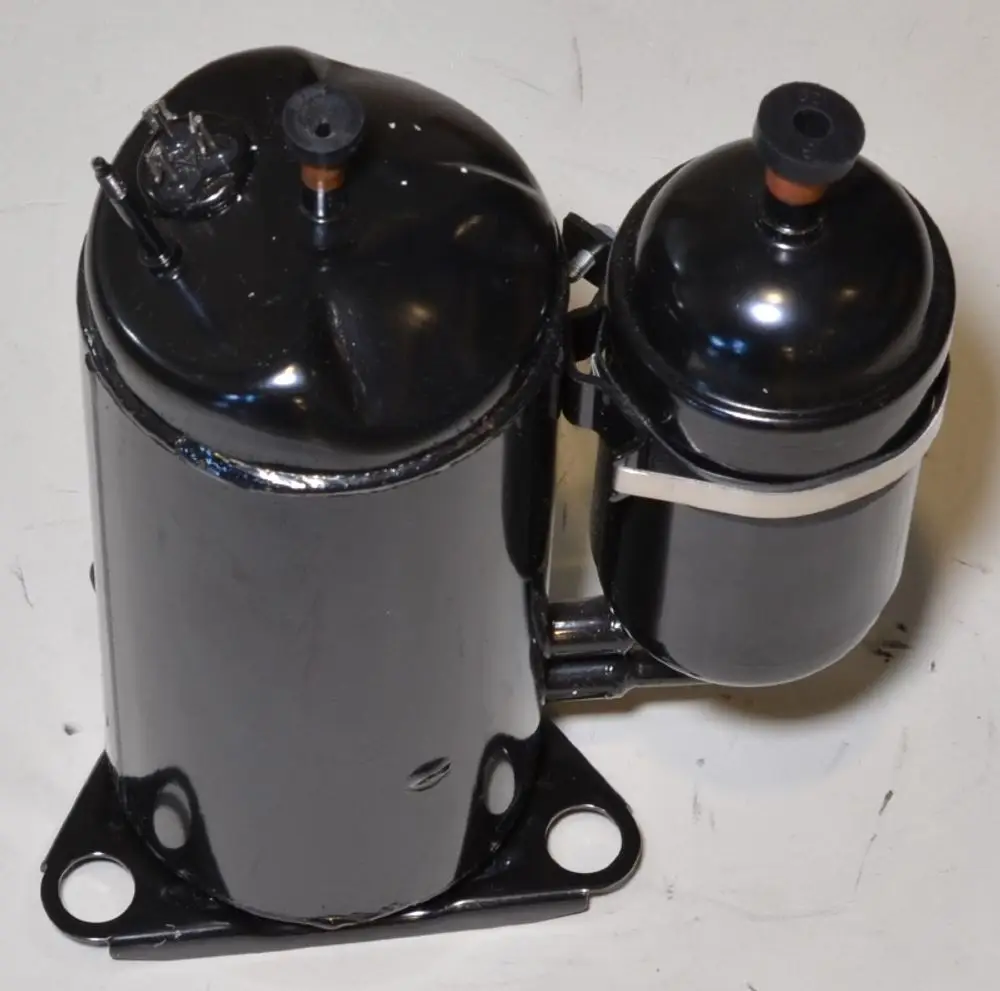 Schwarzer Kompressor von Remko, bestehend aus zwei zylindrischen Behältern, einer größeren und einer kleineren Einheit, mit Anschlüssen oben. Montagesockel vorhanden.