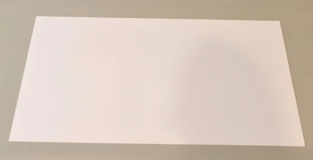 Weißes Kunststoffblatt auf grauem Untergrund, gerade Kanten, flache Oberfläche. Teil eines Luftkanalsystems, möglicherweise von der Marke Remko.