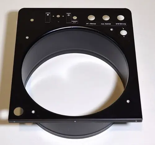 Schwarze Metallplatte mit rundem Gehäuse und mehreren Löchern sowie Beschriftungen. Teil eines Remko-Produktes zur Montage oder Verbindung in einem technischen System.