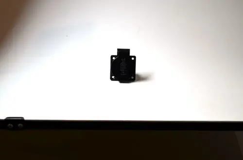 Stecker mit schwarzem Gehäuse und Schaltkontakt, platziert auf einer weißen Oberfläche. Produkt scheint von der Marke Remko zu sein.